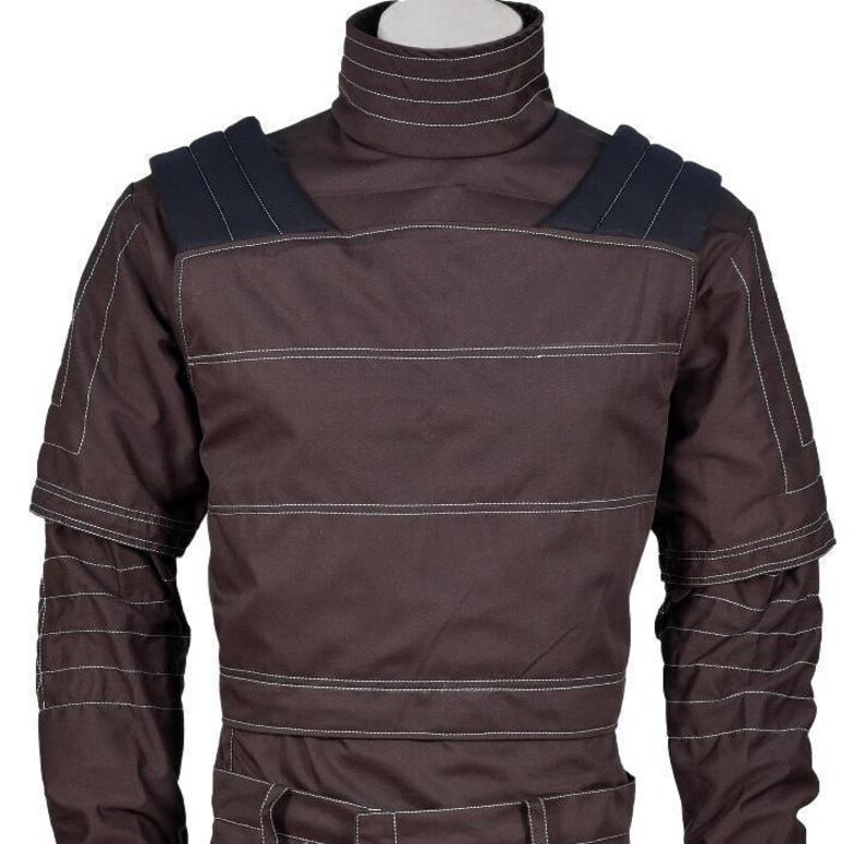 May include: A dark brown long-sleeve shirt featuring a high mock neck collar, horizontal white topstitching, and dark navy blue shoulder panels. The garment includes structured sleeve detailing with multiple rows of white stitching across the arms.
