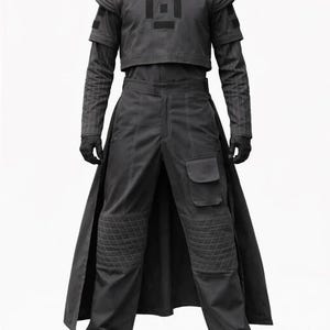 K&ouml;nnte beinhalten: Ein dunkelgraues Outfit bestehend aus einem bauchfreien Oberteil mit geometrischem Design, einer lang&auml;rmeligen Unterschicht und einer hoch taillierten Hose mit Taschen und gesteppten Knieschonern. Das Outfit beinhaltet einen langen, rockartigen Einsatz sowie schwarze Handschuhe und Schuhe.