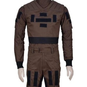 May include: Brown jumpsuit with black accents. The outfit features a high collar, padded shoulders, and multiple rectangular patches. Black bands are on the waist and lower legs. The sleeves have black cuffs.