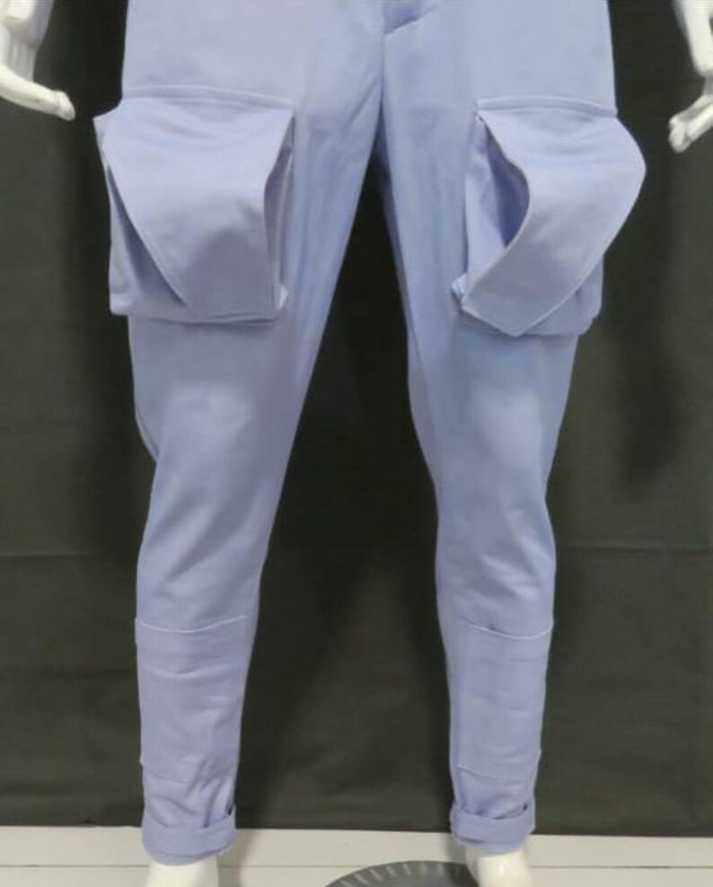 Puede incluir: Pantalones cargo de color azul claro con dos bolsillos de parche grandes y prominentes en la parte delantera de los muslos. Los pantalones tienen un corte recto con un acabado de color s&oacute;lido y detalles de costuras visibles en la parte inferior.