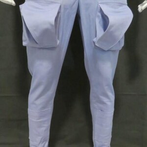 Puede incluir: Pantalones azul claro con bolsillos grandes y distintivos en los muslos. Los pantalones tienen un corte entallado, con dobladillo en los tobillos. La tela es de color liso, adecuada para ropa informal. Largo de la pierna: aprox. 100 cm.