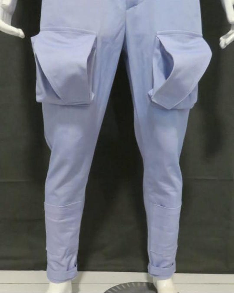 Puede incluir: Pantalones azul claro con bolsillos grandes y distintivos en los muslos. Los pantalones tienen un corte entallado, con dobladillo en los tobillos. La tela es de color liso, adecuada para ropa informal. Largo de la pierna: aprox. 100 cm.