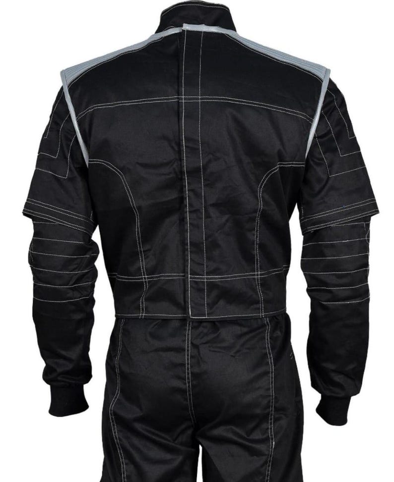 May include: Black racing suit with white stitching and gray accents on the shoulders and collar. The suit has long sleeves with ribbed cuffs and a full-length zipper. The suit is designed for motorsports.