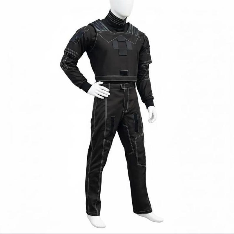 May include: Black tactical outfit with white stitching details, displayed on a mannequin. The outfit includes a cropped jacket with long sleeves, a high collar, and matching pants. The design features reinforced panels and a utilitarian aesthetic.