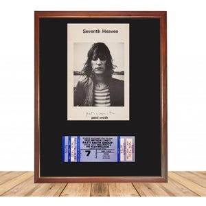 Op de afbeelding: Een ingelijste zwart-witfoto van Patti Smith met daaronder een concertkaartje. De foto is getiteld "Seventh Heaven" en bevat haar handtekening. Het kaartje is blauw en wit.