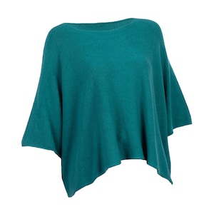 Könnte beinhalten: Ein teal-farbener Poncho-Pullover mit Bootsausschnitt und kurzen Ärmeln. Das Strickkleidungsstück hat eine lockere Passform und einen leicht asymmetrischen Saum. Der Stoff wirkt weich und fällt locker.
