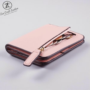 May include: A pale pink leather wallet with a gold zip and a small compartment containing coins. The wallet is open, revealing the interior. The edges are a darker shade of pink. The text "Zee Craft Leather" is visible in the upper left corner.