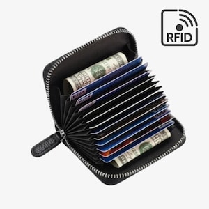 May include: A black accordion-style wallet with a zip closure, featuring multiple interior slots filled with various credit cards and folded banknotes. The wallet includes an RFID protection symbol in the upper right corner.
