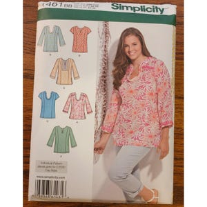 May include: A Simplicity sewing pattern envelope 1461 BB for a tunic top. The front shows six variations of the tunic with different sleeve lengths, necklines, and fabric prints. A photograph displays a model wearing a pink and white floral tunic.