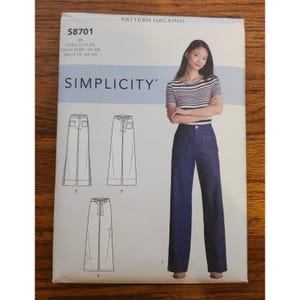 Puede incluir: Patrón de costura Simplicity S8701 con pantalones de pernera ancha. El patrón incluye información de tallas en tallas de EE. UU., Euro y francesas. La imagen muestra a una mujer con una camiseta a rayas y pantalones vaqueros. El patrón está etiquetado como "Pattern Hacking."