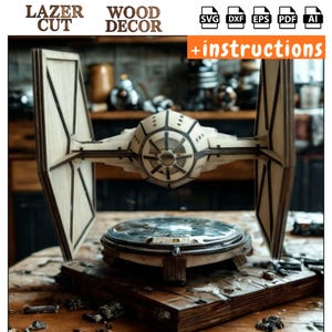 May include: A laser-cut wooden TIE fighter model, a wood decor item. The model is light brown with dark brown accents, and is displayed on a wooden base. The image includes the text "LAZER CUT" and "WOOD DECOR".