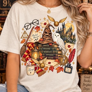 May include: A cream-colored t-shirt featuring a graphic print of a wizarding hat, a white owl, a castle, books labeled Spells, Potions, Herbology, Divination, and Charms, a broom, glasses, a mug with the text Always, and an inkwell with Magic Awaits.