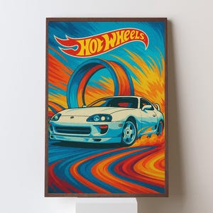 May include: A framed print featuring a white sports car speeding on a colorful track. The Hot Wheels logo is at the top, with a blue and orange background. The artwork has a retro style.
