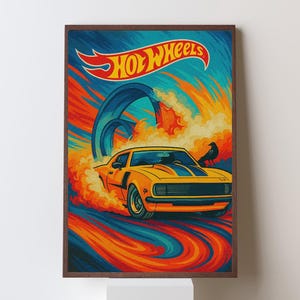 May include: A framed print featuring a yellow Hot Wheels car speeding through a colorful track. The artwork has a retro style with the Hot Wheels logo at the top. The background is a mix of blue, orange, and yellow.