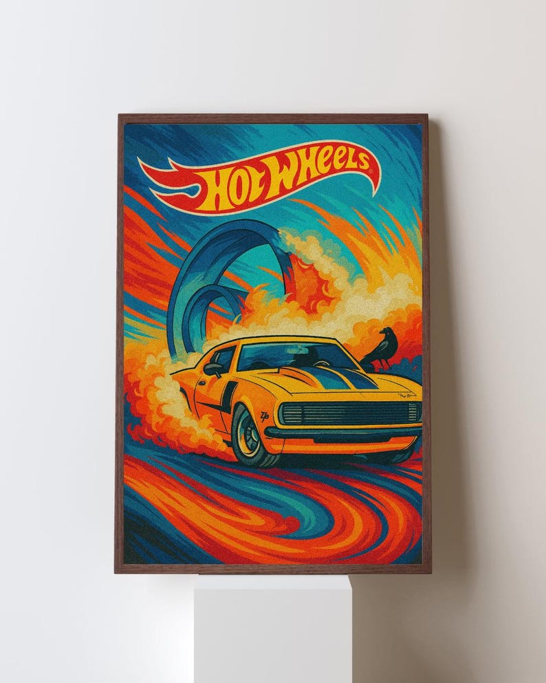 May include: A framed print featuring a yellow Hot Wheels car speeding through a colorful track. The artwork has a retro style with the Hot Wheels logo at the top. The background is a mix of blue, orange, and yellow.