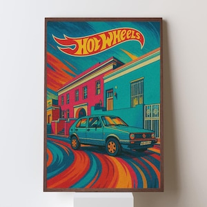 May include: A framed print featuring a vintage teal car with orange wheels, parked on a street with colorful buildings. The Hot Wheels logo is displayed at the top. The artwork has a retro, stylized design with vibrant colors.