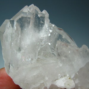 Puede incluir: Un grupo de cristales de cuarzo transparentes de diferentes formas y tamaños. Los cristales son translúcidos y tienen un brillo vítreo.