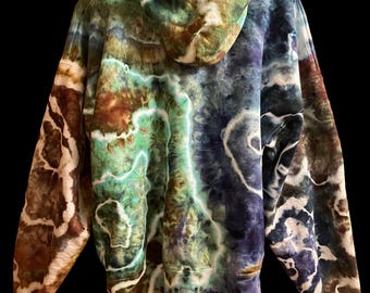 May include: A long-sleeve hooded sweatshirt featuring a multi-colored tie-dye pattern with swirling organic shapes in shades of deep blue, forest green, earthy brown, and bright turquoise, accented by stark white lines throughout the fabric.
