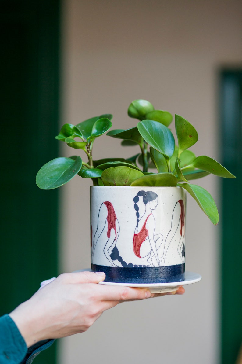 Hand-painted ceramic planter with sequential illustrations of a forward roll with a drainage hole and saucer image 1