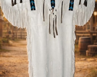 May include: A white fringed dress with black and turquoise geometric patterns on the yoke. The dress has long fringe along the sleeves and hemline, and is hanging on a black hanger.