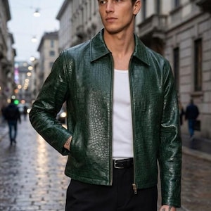 May include: A dark green jacket with a textured crocodile-skin pattern, featuring a classic collar, long sleeves, and a full-length front zipper. The jacket is worn over a plain white tank top and paired with black trousers and a black leather belt.