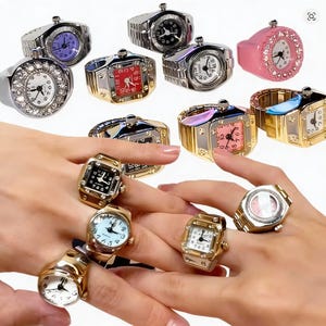 May include: A collection of ring watches in various styles and colors. The watches feature round and square faces with different colored dials, including black, white, pink, and purple. Some rings are silver-toned, gold-toned, or pink, and some are adorned with rhinestones.