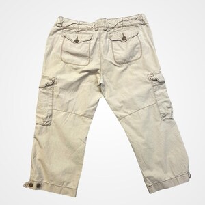 Puede incluir: Pantalones cargo color caqui con múltiples bolsillos y detalles de botones. Los pantalones tienen un corte relajado y están hechos de una tela duradera. La parte trasera presenta dos bolsillos con solapa abotonados.