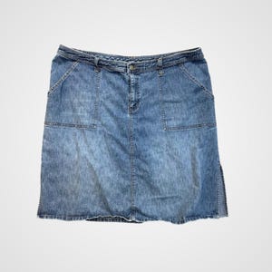 Könnte beinhalten: Hellblauer Jeansrock mit Knopfverschluss und Gürtelschlaufen. Der Rock hat zwei Vordertaschen und einen Schlitz an der Seite. Der Jeansrock ist ein klassischer Stil.