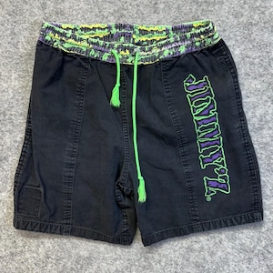 May include: Black shorts featuring a neon green and purple patterned elastic waistband with a matching neon green drawstring. The word JIMMY'Z is printed vertically in a stylized neon green and purple font on the lower right leg area.
