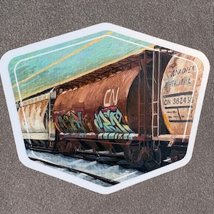 May include: A sticker depicting a brown CN Canadian National train carriage with graffiti art. The sticker has a white border and a light blue sky background. The train carriage has the text "CN 382436" and "Canadian National".