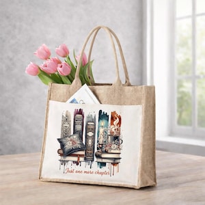 May include: A beige jute tote bag with a white pocket featuring a watercolor illustration of books, candles, and a teacup. The bag contains pink tulips and a magazine. The text on the pocket reads "Just one more chapter."