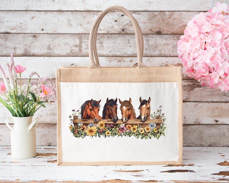 May include: A beige tote bag with a white panel featuring a watercolor illustration of four horse heads peering over a wooden fence adorned with colorful flowers. The bag has a sturdy, woven handle.