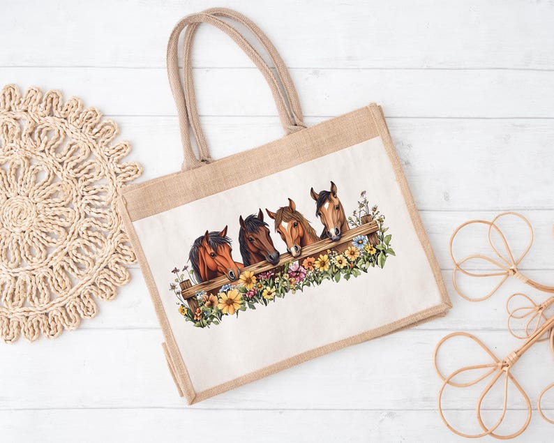 May include: A beige tote bag with a rectangular image of four horse heads peeking over a wooden fence. The fence is surrounded by colorful flowers. The bag has two beige handles and is made of a natural-looking material.