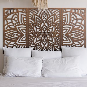 May include: A three-panel wooden headboard with a detailed, symmetrical floral design. The panels are a warm brown color and are placed above a bed with white pillows and bedding. The headboard adds a decorative element to the bedroom.