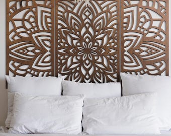 May include: A three-panel wooden headboard with a detailed, symmetrical floral design. The panels are a warm brown color and are placed above a bed with white pillows and bedding. The headboard adds a decorative element to the bedroom.