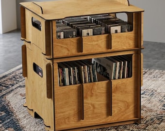 May include: A two-tiered light brown wooden storage crate designed for media organization. The unit features open-front compartments for storing compact discs and vinyl records, with integrated side handles and a flat top surface for display.