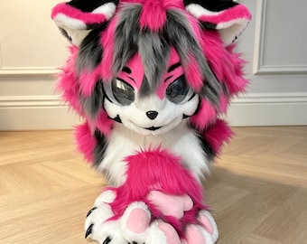 Könnte beinhalten: Eine Plüsch-Tierkopfmaske aus langem Kunstfell in leuchtendem Pink, Grau und Weiß. Die Maske hat große, glänzende schwarze Augen, spitze Ohren mit schwarz-weißen Streifen und eine kleine schwarze Nase. Dazu gehören passende Pfoten mit rosa Ballen.