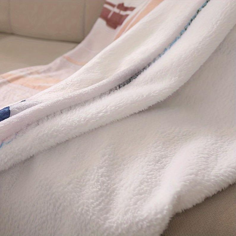May include: A soft, white plush blanket with a folded edge. The blanket has a patterned design in shades of brown, peach, and blue. The blanket is made of a fluffy, textured material, perfect for snuggling.