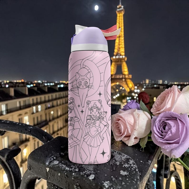 May include: A pink water bottle featuring a cartoon design with a purple lid and a white and red accent. The bottle has a black outline design of a cat and a female anime character. The Eiffel Tower is in the background.