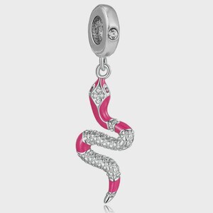 May include: A silver-toned snake charm featuring vibrant pink enamel detailing along the head and tail. The body is textured with a metallic scale pattern and accented with small clear stones embedded in the head and mid-section of the snake.