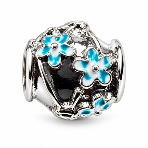 May include: A silver charm bead featuring a polished metallic finish with three raised flower motifs. Each flower has white petals with bright blue gradient centres. The background of the bead is filled with a smooth, glossy black enamel inlay.