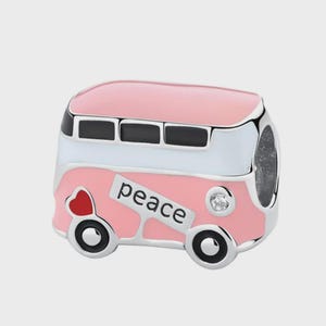 May include: A silver-toned charm shaped like a van, featuring pink and white enamel detailing. The side displays the word peace in black lettering, a small red heart, and a single clear stone accent. The windows are outlined in black enamel.