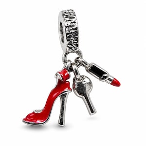 May include: A silver-toned charm bead featuring three dangling pendants: a bright red high-heeled shoe, a smooth silver heart, and a black and red lipstick tube. The main bead has a textured, rugged surface and a central hole for a bracelet chain.