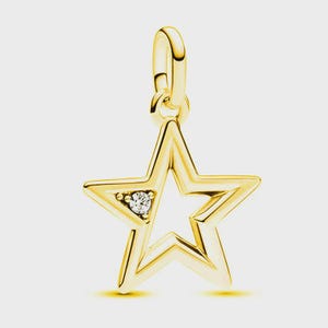 May include: A gold star-shaped pendant featuring a polished metallic finish and a single clear, round-cut gemstone set into one of the star's points. The pendant includes a small, integrated circular bail at the top for attachment to a chain.