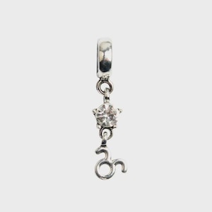 Pode incluir: Um pingente de metal prateado com uma argola circular no topo, uma gema redonda transparente e facetada em uma moldura em forma de estrela e o símbolo do zodíaco de Touro pendurado na parte inferior, conectados por pequenos anéis de metal.