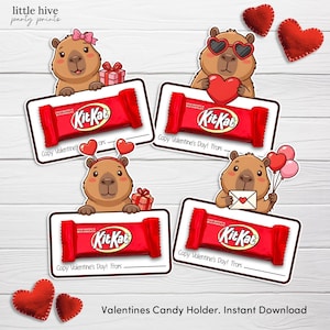 May include: Valentine's Day candy holders featuring cartoon capybaras holding Kit Kat bars. Each capybara has a different Valentine's Day accessory, such as heart-shaped sunglasses or a bow. The holders are red and white, with space to write a message.