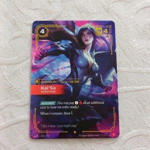 以下が含まれることがあります： 紫と青の配色で、未来的な衣装を着た女性キャラクターのイラストが描かれたトレーディングカード。カードの2つの角には数字の4があり、「Kai'Sa Survivor」というテキストがあります。カードには「I like it here. I just might stay.」というテキストもあります。