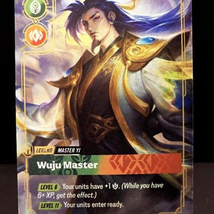 May include: A trading card with an illustration of a character with blue hair and gold detailing. The card is labelled "Wuju Master" and includes game text. The card is displayed on a clear plastic stand.