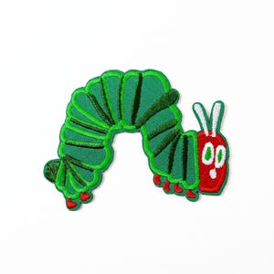 Può includere: Toppa ricamata raffigurante un bruco verde con testa rossa e piedi rossi. Il bruco ha un corpo segmentato con contorni verde scuro e un volto sorridente. La toppa è progettata per l'applicazione su abbigliamento o accessori.
