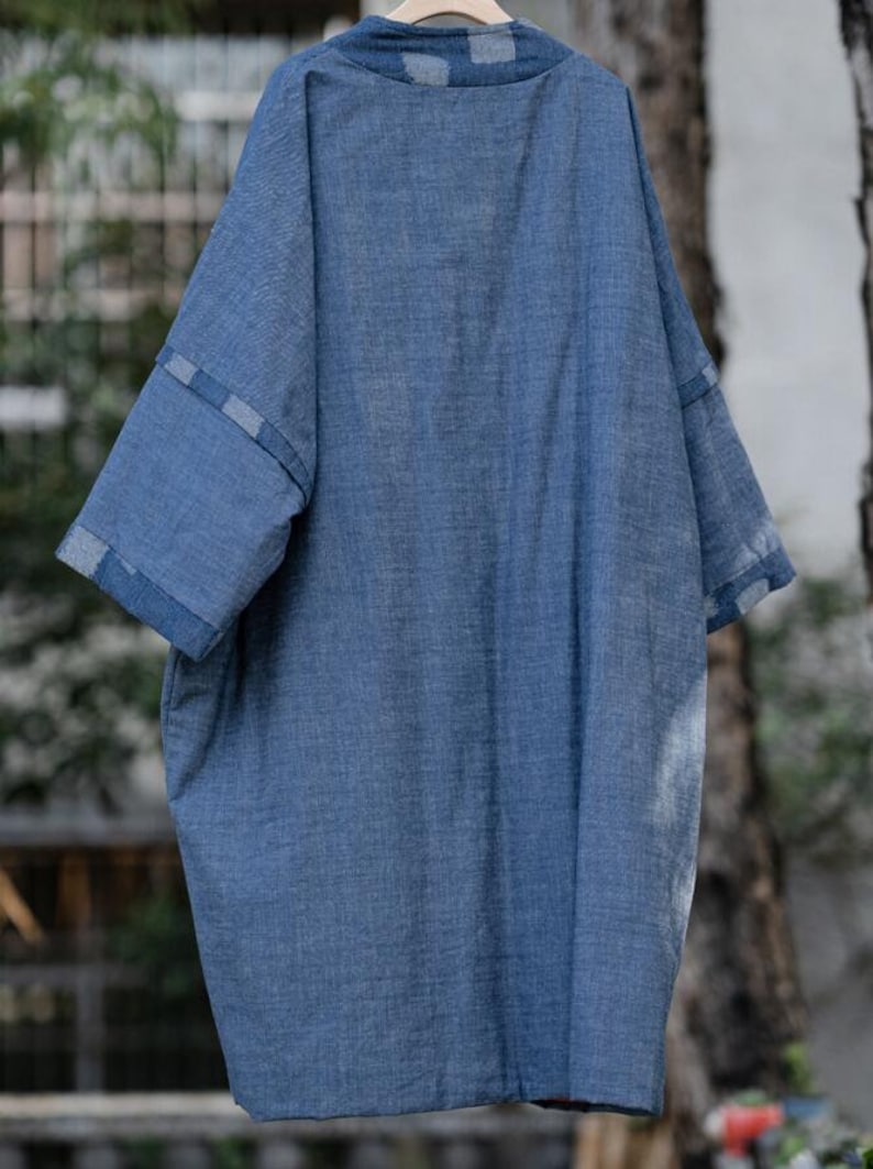 Może przedstawiać: Koszula z niebieskiego denimu o luźnym kroju i lekko oversizowym fasonie. Koszula zapinana jest na guziki z przodu i ma kołnierzyk. Rękawy są trzyczwarte i mają biało-niebieski wz&oacute;r w kratkę na mankietach.